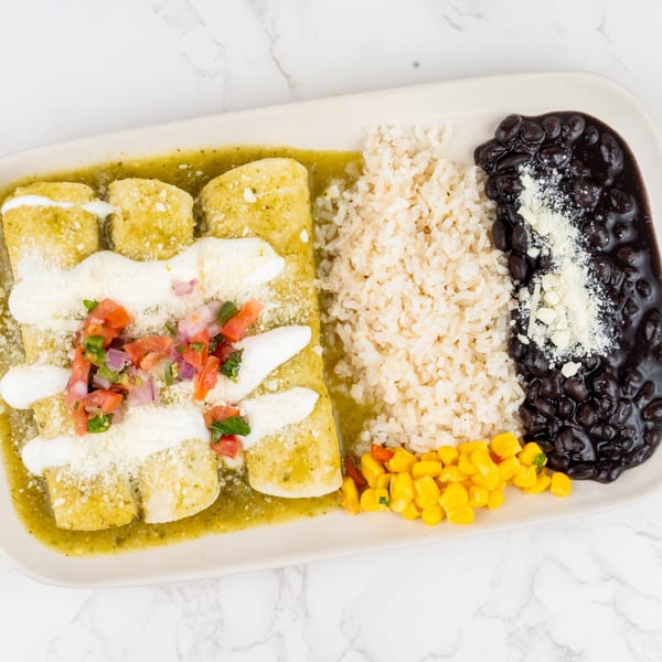 Green enchiladas with rice, black beans, corn, and pico de gallo on a white platter.